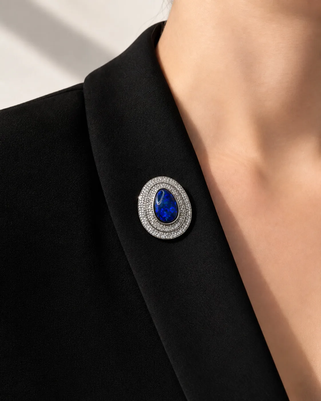 Blue gemstone and diamond brooch worn on a black lapel