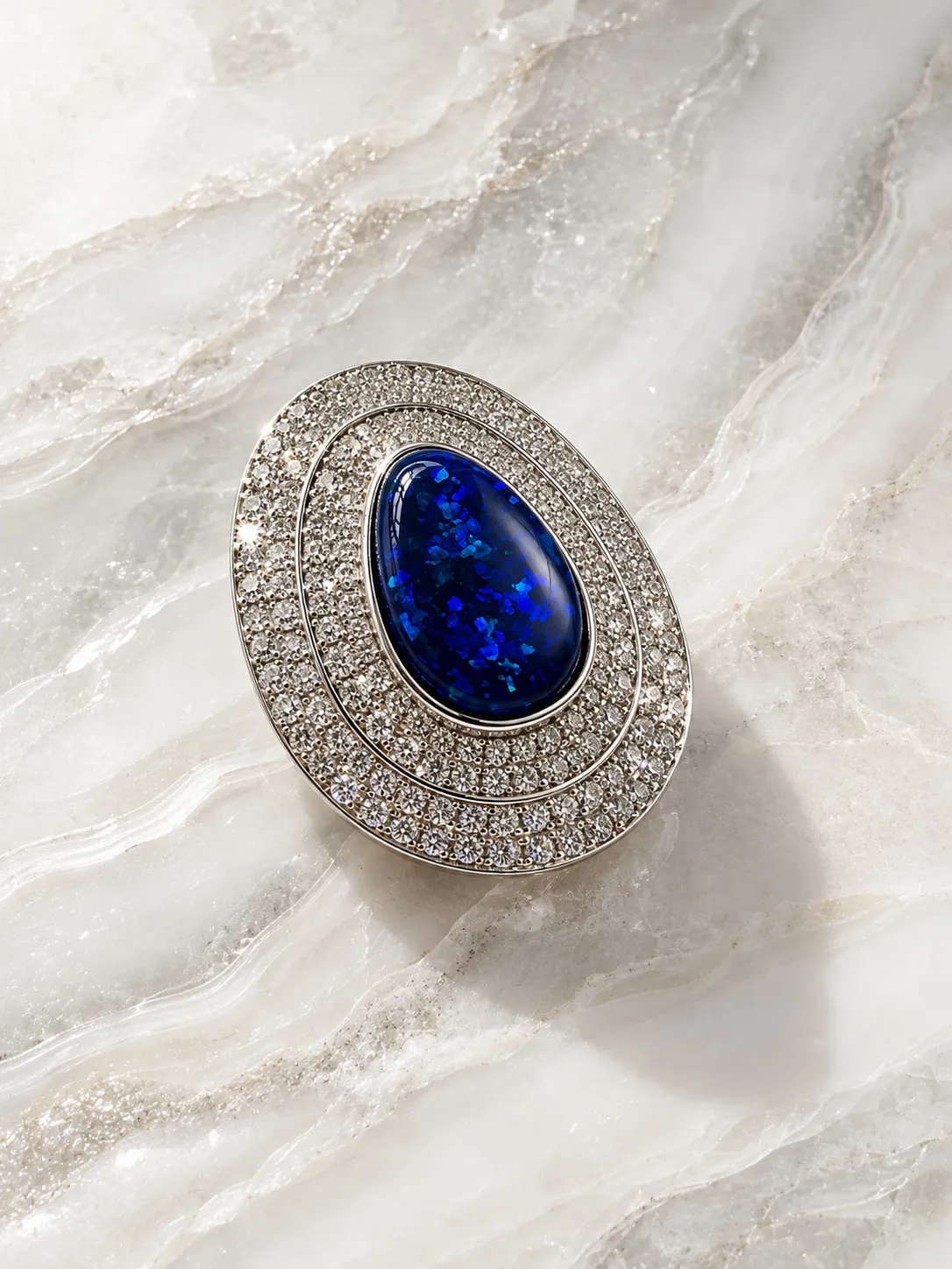 Oval blue gemstone ring surrounded by diamonds on marble