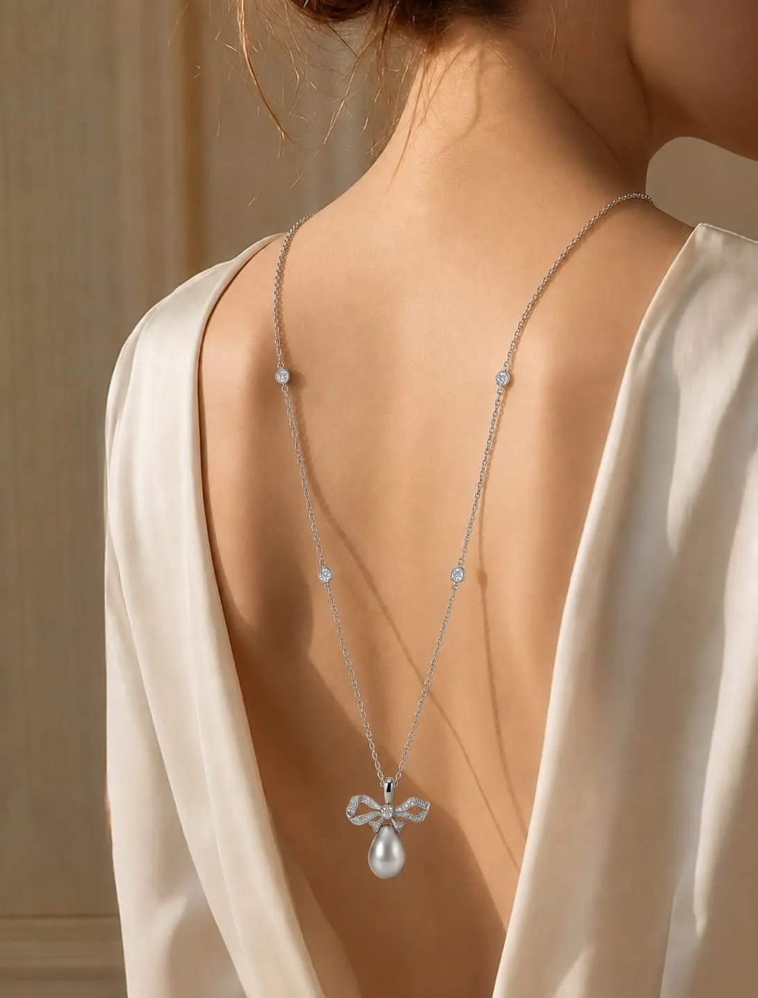 Diamond bow pendant with a pearl drop worn down the back