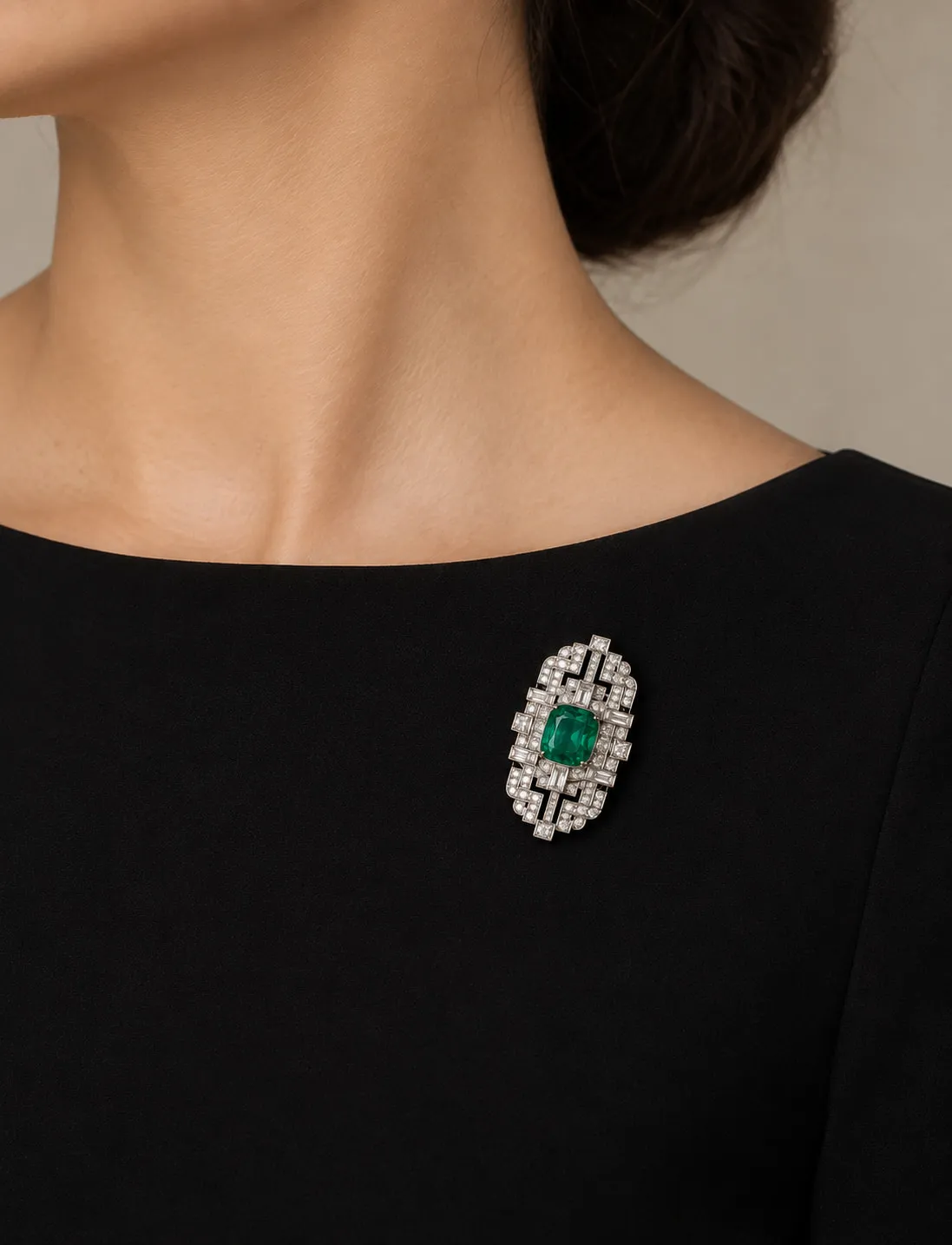 Art deco diamond brooch with an emerald centre, worn on black