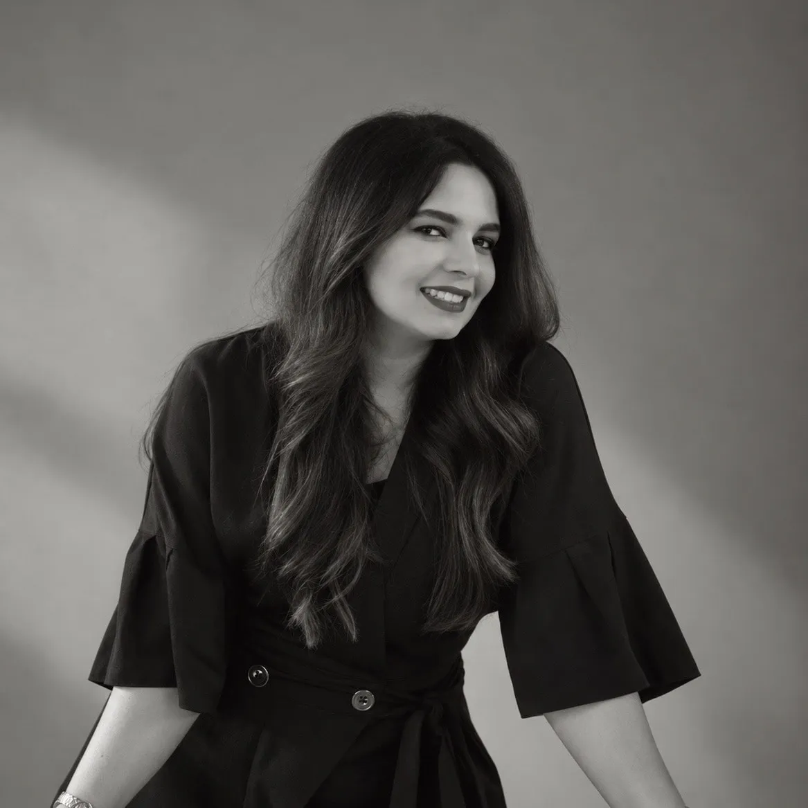 May AlFassam smiling, seated, in a black and white portrait
