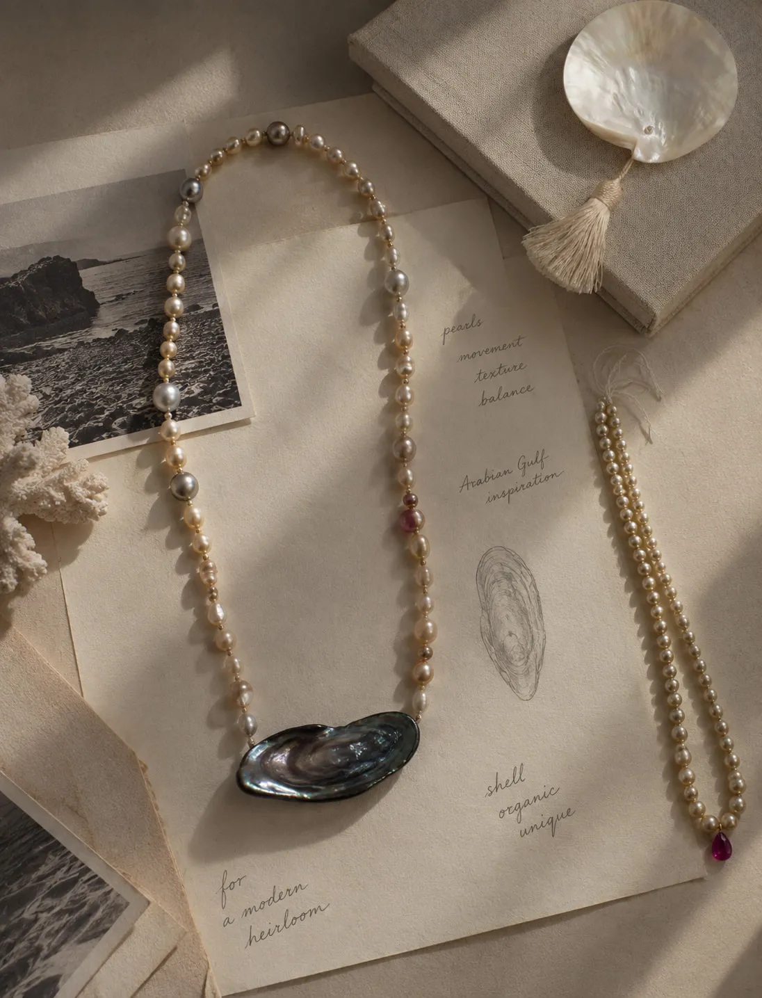 Pearl and abalone necklaces laid over design notes
