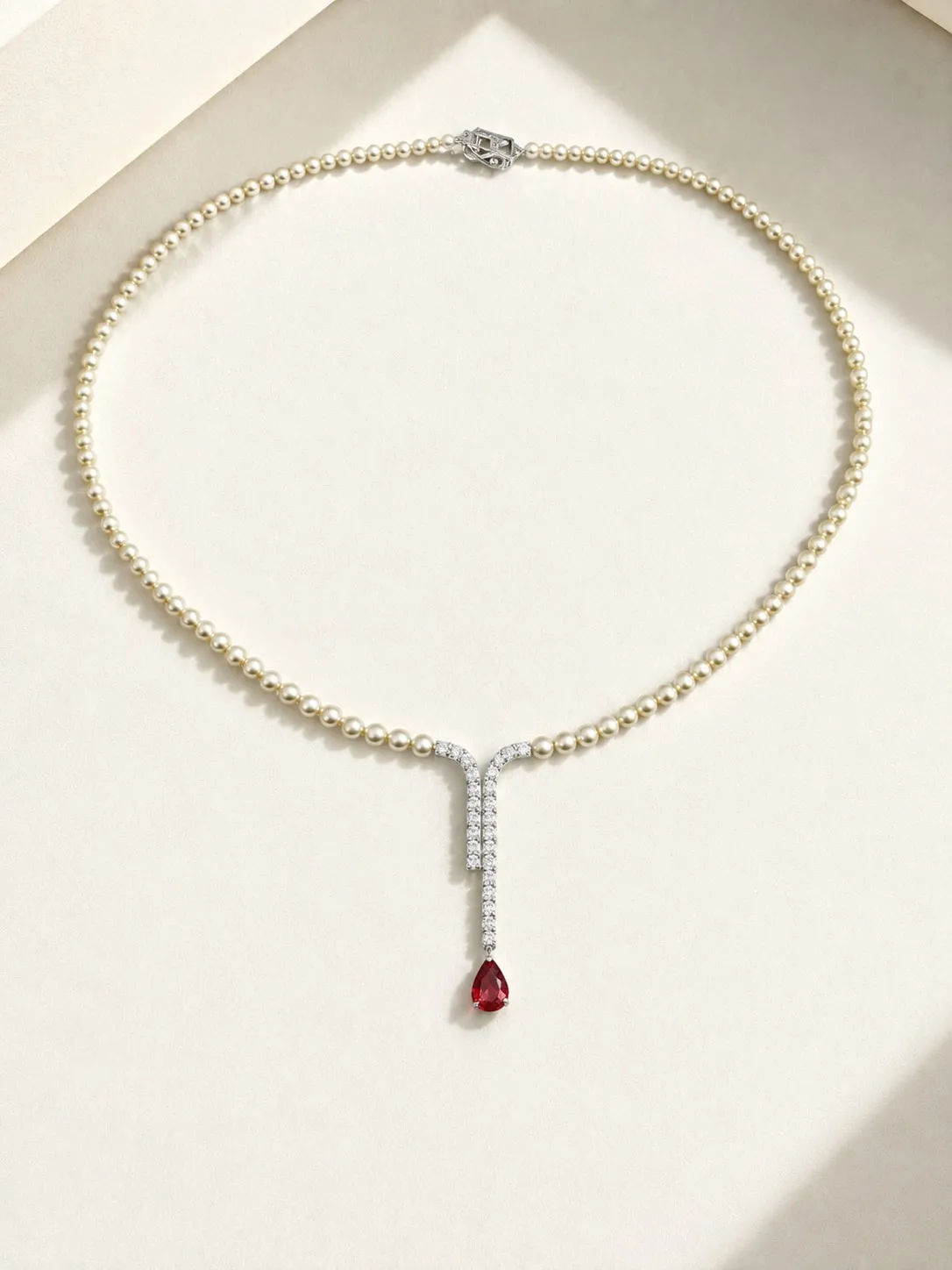 Fine pearl necklace with a diamond bar and a red gemstone drop