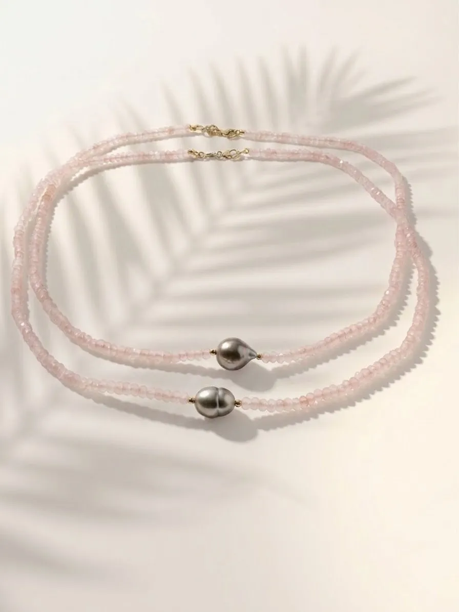 Pale pink bead necklace with dark pearls beneath the shadow of a palm leaf