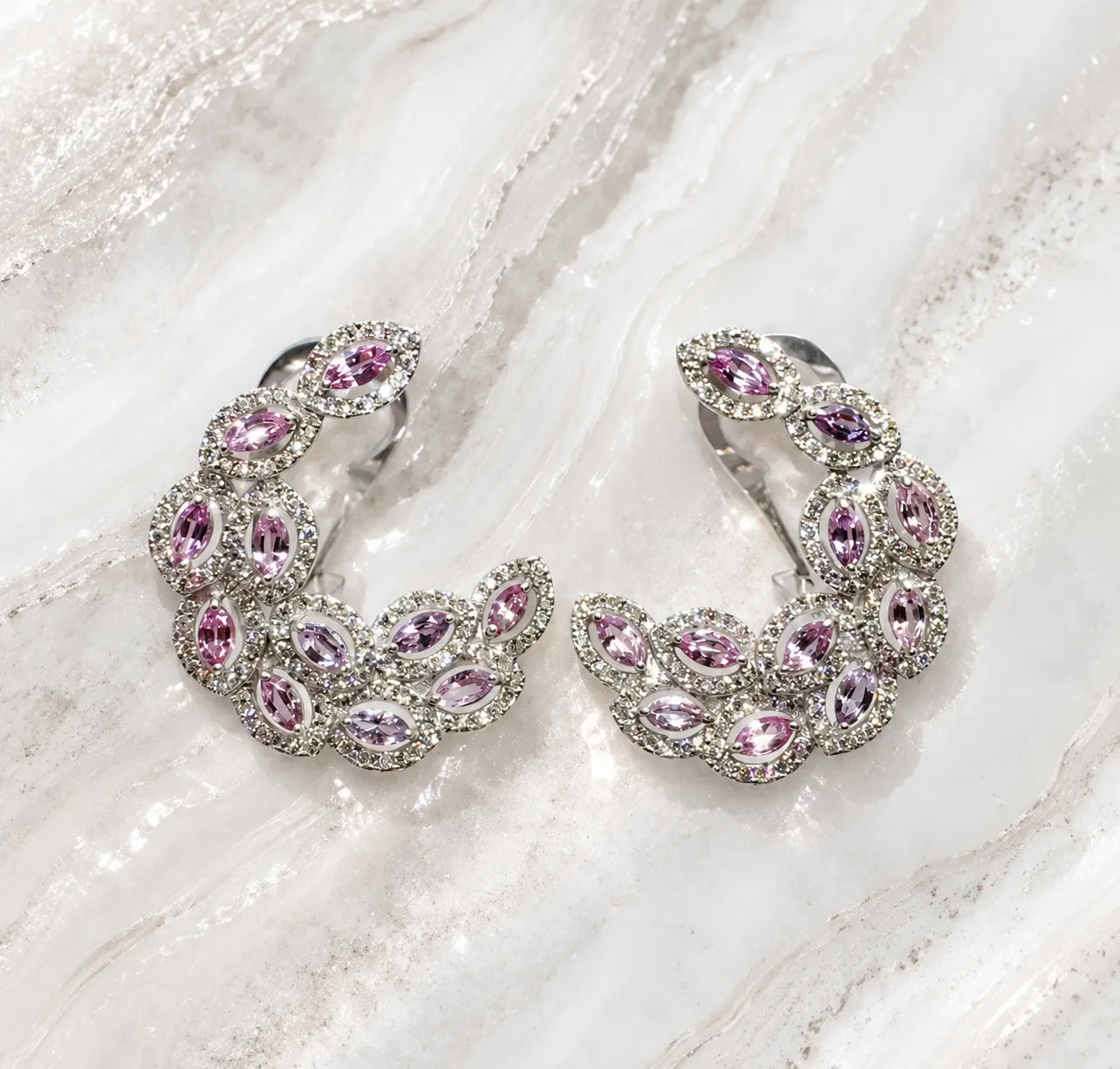 Diamond and pink gemstone leaf earrings on marble
