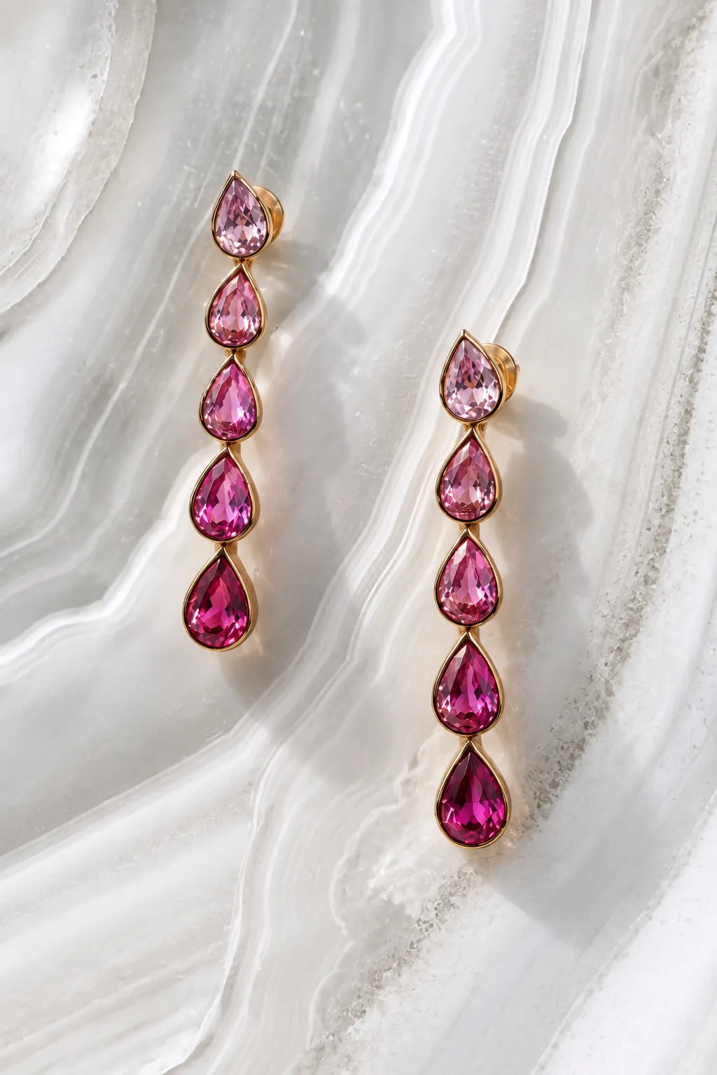 Drop earrings of graduated pink pear-shaped gemstones in gold