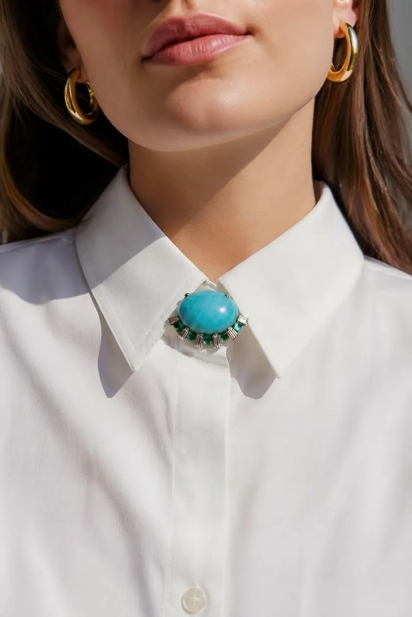 Turquoise pendant worn at the collar of a white shirt